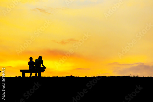 son and dad sitting on Chair at colorful sunset on background © thechatat