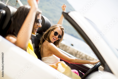 Young women in white cabriolet car driving everywhere and looking for freedom and fun