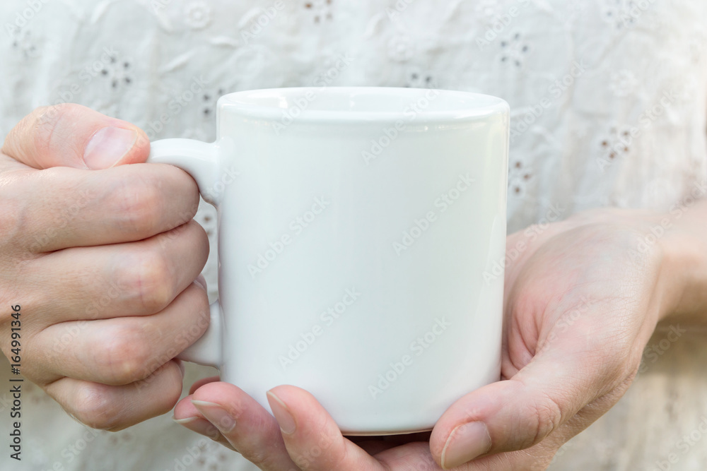 Young caucasian woman holding a white mug, mock up, blank space for text,  artwork, hands, linen shirt, natural authentic, kinfolk style, soft light  Stock Photo