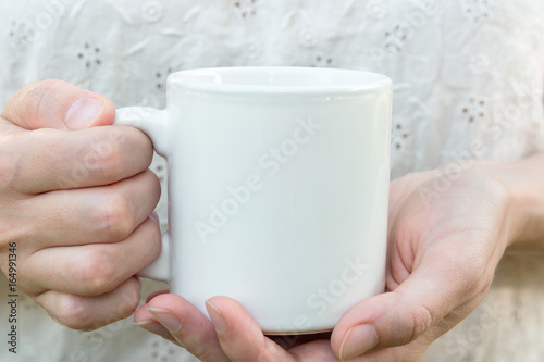 Young caucasian woman holding a white mug, mock up, blank space for text, artwork, hands, linen shirt, natural authentic, kinfolk style, soft light