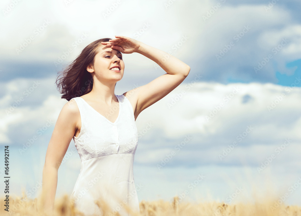 Beautiful and happy girl in a white dress walking in a meadow at summer. Beautiful and happy girl in a white dress walking in a meadow at summer.