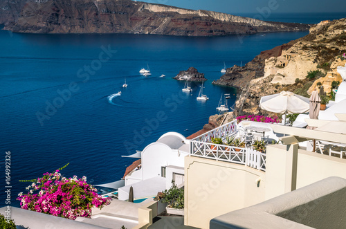 Oia Village  Santorini Cyclade islands  Greece. Beautiful view of the town with white buildings blue church s roofs and many coloured flowers.