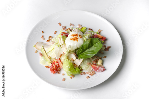 Mix salad with egg poached and chicken on a white plate