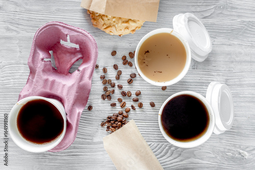 Coffee to go. Coffee cups with cover, coffee beans and cookies on wooden table backound top view photo