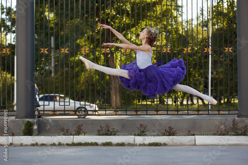 Young beautiful ballerina dancing outdoors in a park. Full length portrait.