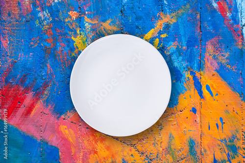 Top view of empty white plate put on colorful table with space for copy. photo