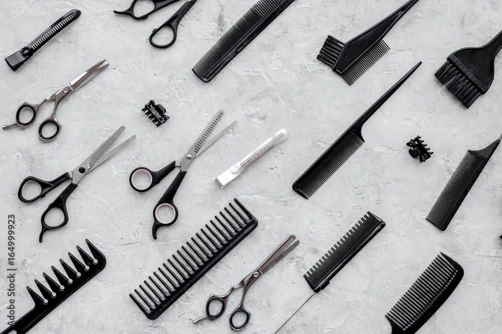 Pattern of combs and hairdresser tools on grey table background top view