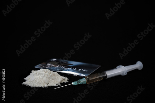 Drug syringe and cooked heroin isolated on black background