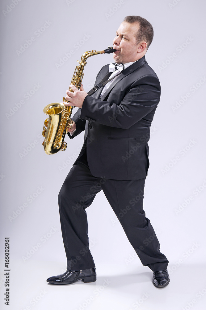 Fototapeta premium Playing the saxophone. Man. European. He plays the saxophone. Dressed in a suit.