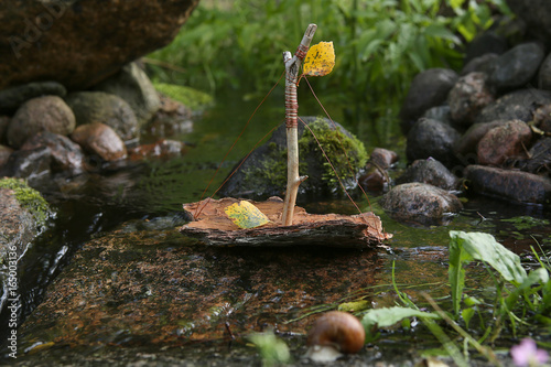 Handmade boat made from tree bark. Boats game in nature. Ship sailing in stream. photo