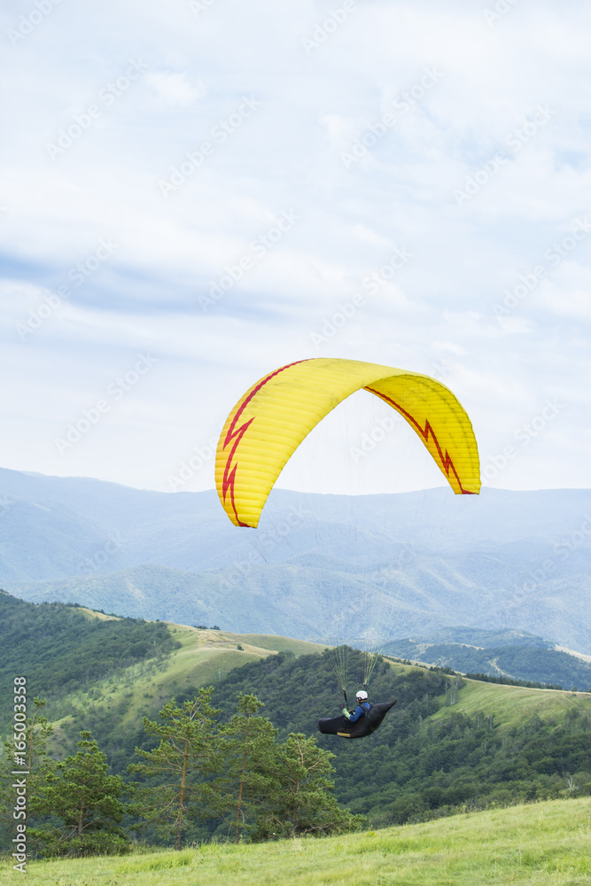Paragliding in the sky. Paraglider flying over a mountain valley in summer sunny day. Paragliding in the sky. Paraglider flying over a mountain valley in summer sunny day.