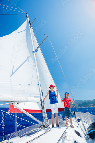 Boy with his sister on board of sailing yacht on summer cruise.