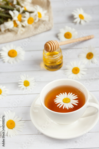 A Cup of chamomile tea and honey on white wooden background