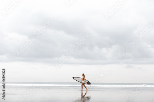 teenage girl in a yellow bikini with her surfboard at a hawaii beach