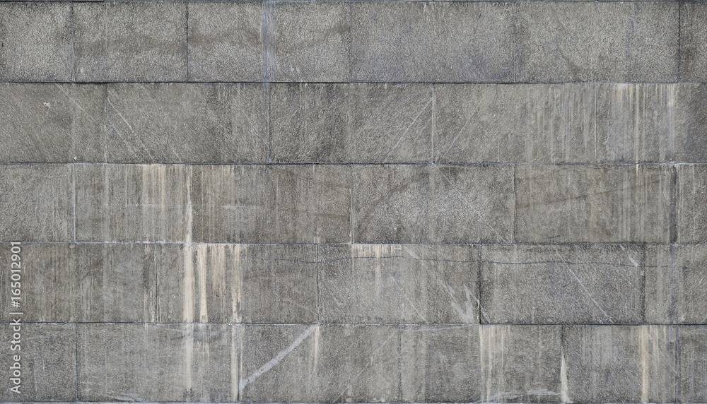 The texture of a wall of large granite tiles that are covered with