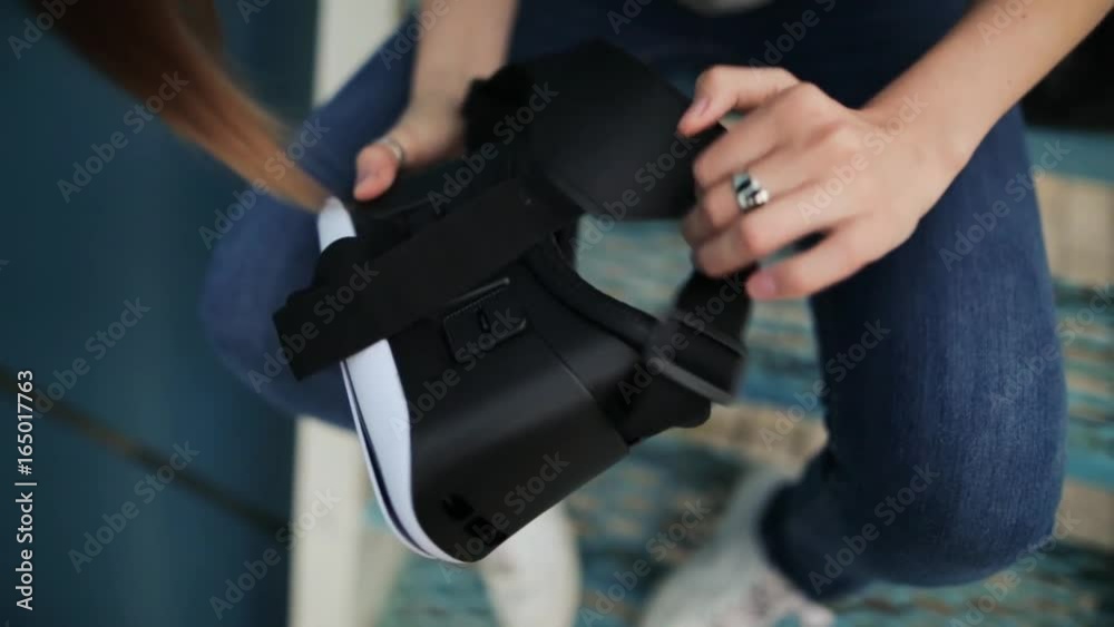 Young girl with a small hands holding virtual reality glasses on a blue background in the evening. Blue background.