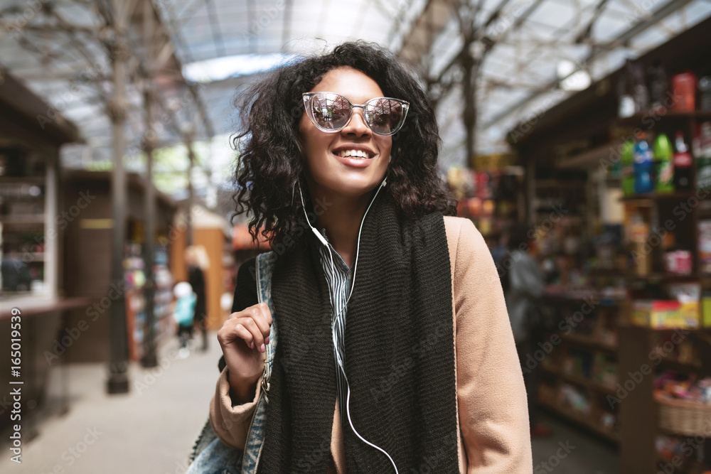 Φωτογραφία Cool African American girl standing on street in earphones