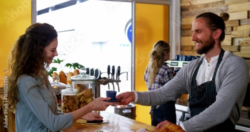Waiter serving coffee to female costumer at counter