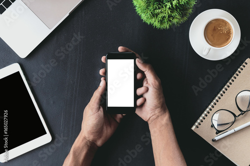 close-up on hand holding phone showing white screen on desk