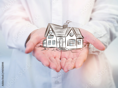 The Architecture, building, house,home,construction, real estate and property concept - close up of hands holding house or home model.Female hand holding house ,real estate agent.