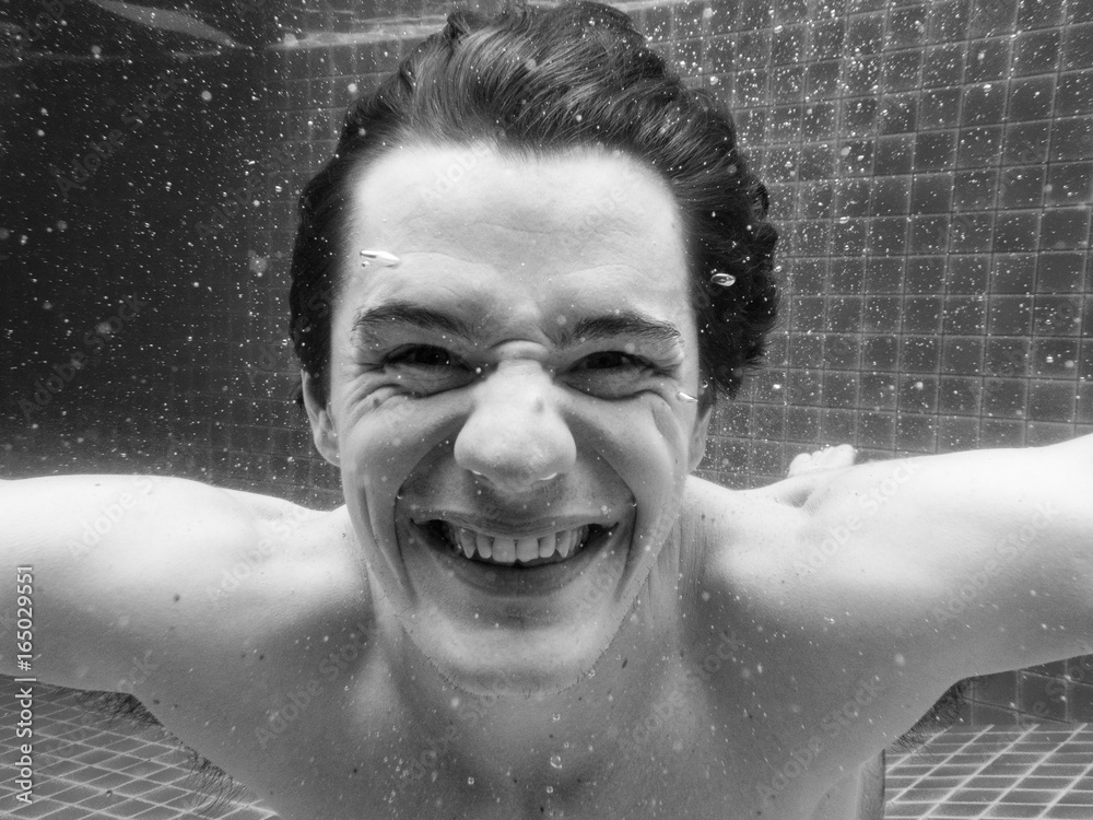 Caucasian man smiling underwater in swimming pool grayscale
