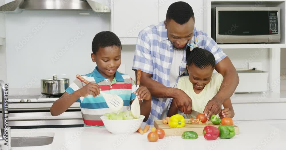 Father and children preparing vegetable salad in kitchen Father and children preparing vegetable salad in kitchen