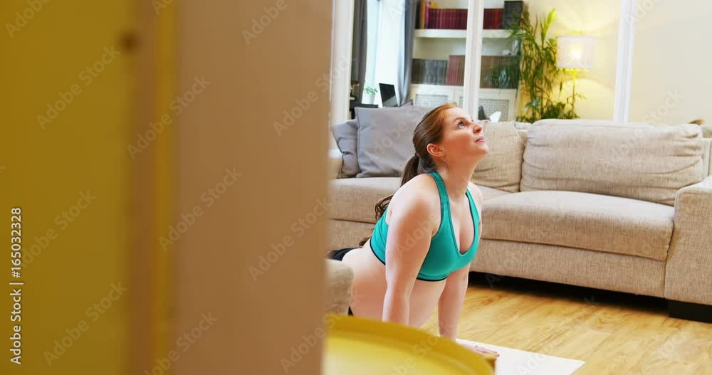 Pregnant woman practicing yoga in living room Pregnant woman practicing yoga in living room