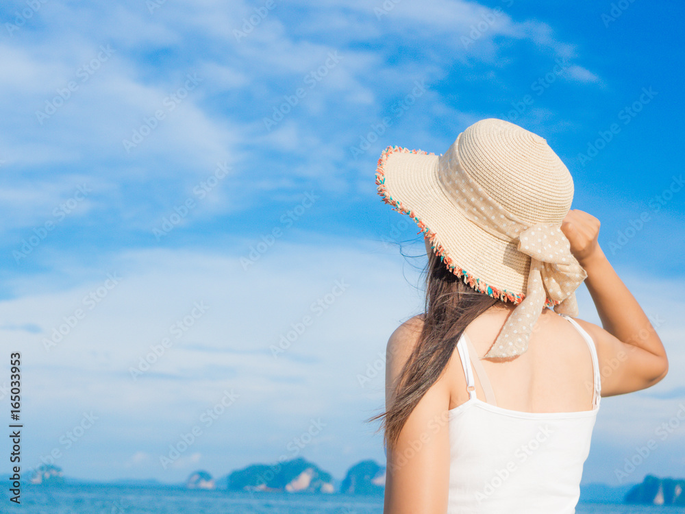 Woman in summer vacation wearing summer hat and beach dress looking the  beautiful view at the ocean