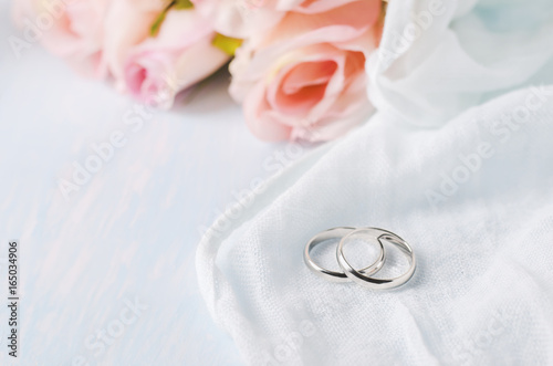 Wedding rings with roses on blue wooden table