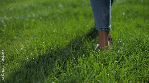Close up of barefooted young girl walking on grass