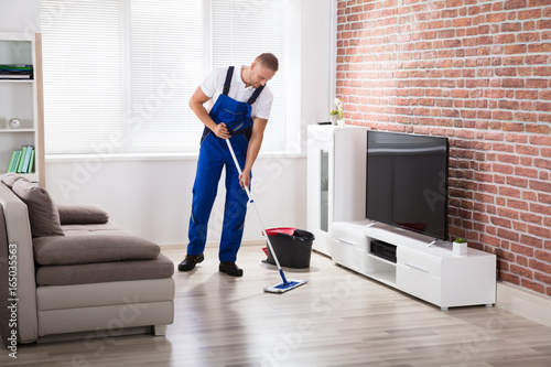 Male Janitor Sweeping Floor At Home