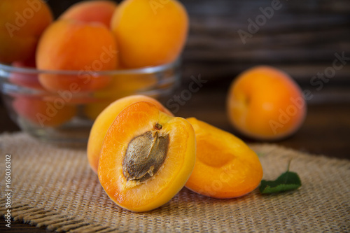 Freshly organic whole and halved apricots in a bowl on a wooden table. Close-up