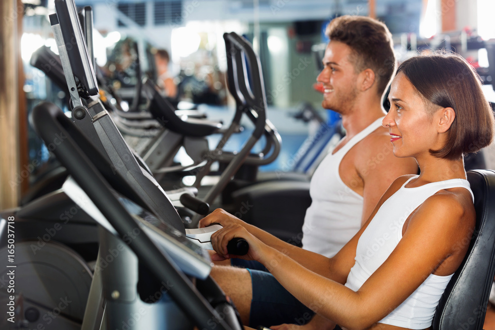 Woman and man using bicycle gym machinery together