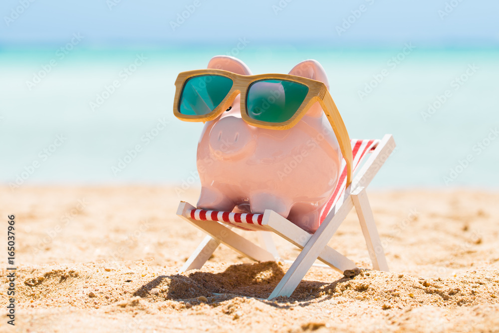 Piggy Bank With Wooden Sunglasses On The Deck Chair - obrazy, fototapety, plakaty 