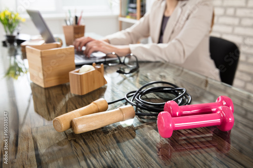 Pink Dumbbells With Skipping Rope On Glass Office Desk