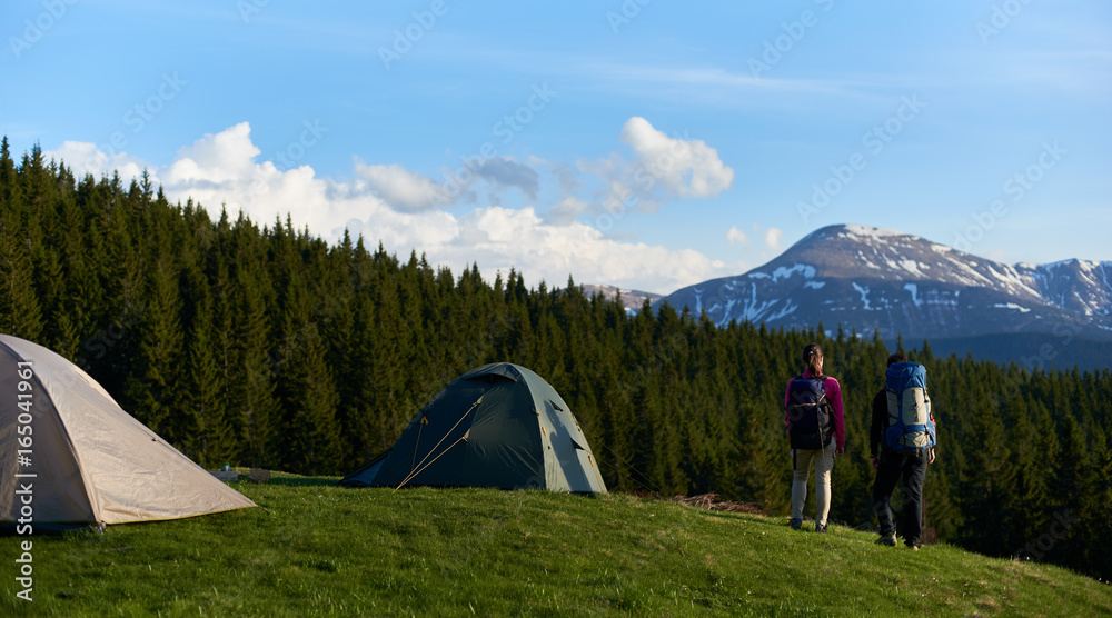 Full length shot of two female hikers with backpacks enjoying stunning view from the top of a hill while camping and hiking in the mountains friendship achievement nature peaceful freedom.