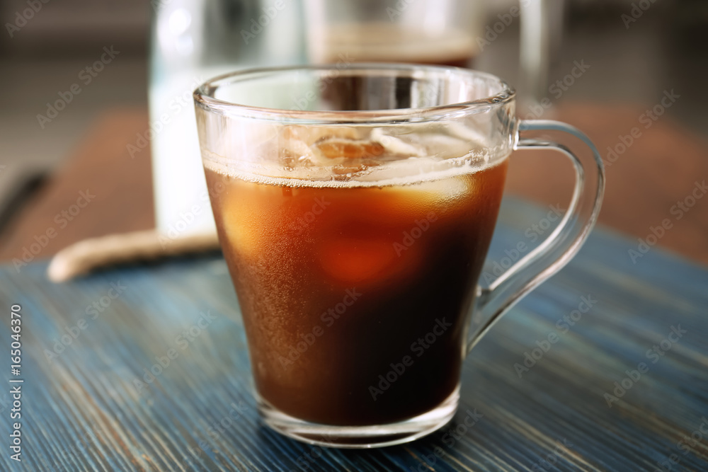 Glass cup of cold brew coffee on wooden tray Glass cup of cold brew coffee on wooden tray