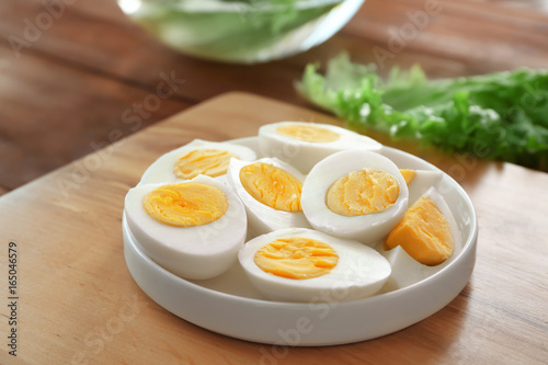 Ceramic plate with hard boiled eggs on wooden surface. Nutrition concept