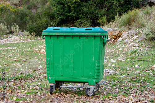  Metal green garbage can with wheels in countryside
