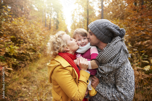 Joyful scene of parents kissing daughter