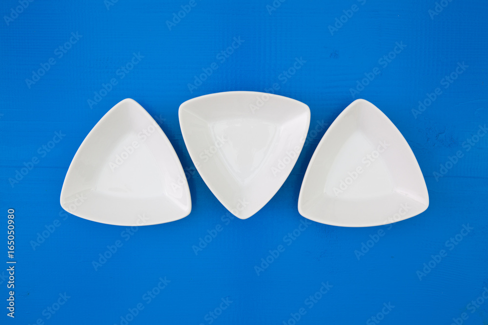 Empty triangular ceramic bowls for sushi on the blue wooden table Empty triangular ceramic bowls for sushi on the blue wooden table