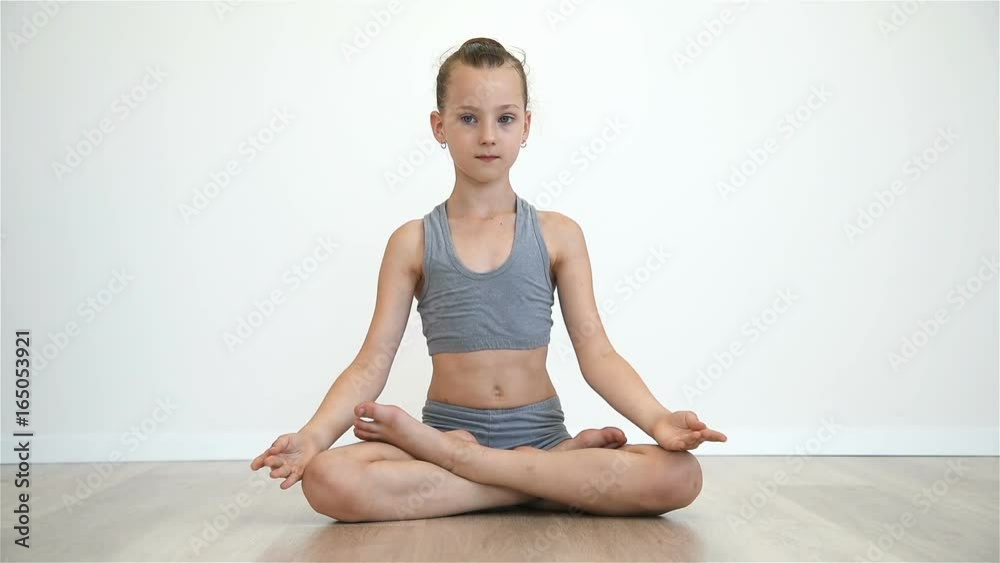 Little Girl Doing Namaste Sitting On Floor In Lotus Position. Slow Motion Effect Little Girl Doing Namaste Sitting On Floor In Lotus Position. Slow Motion Effect