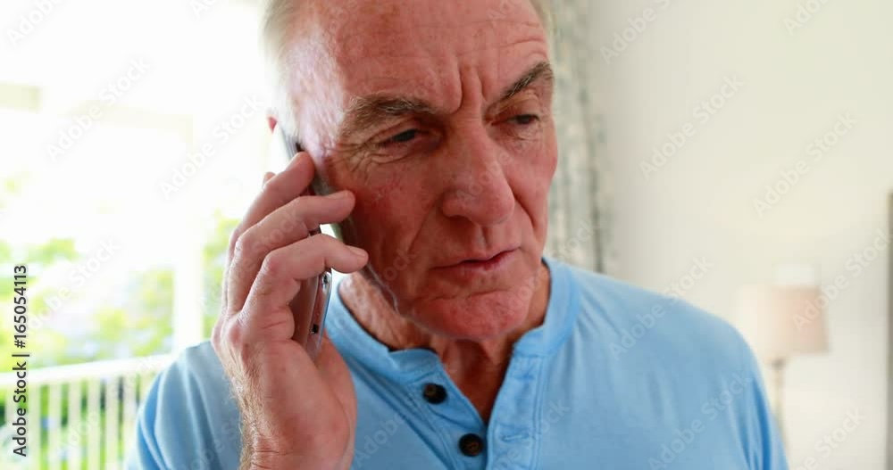 Senior man talking on mobile phone while senior woman resting in bedroom Senior man talking on mobile phone while senior woman resting in bedroom