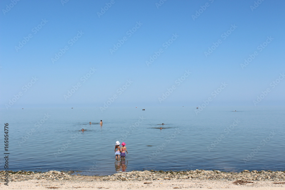 The calm sea in the morning and little girls on the beach The calm sea in the morning and little girls on the beach