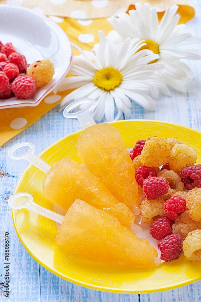 Yellow fruit ice-cream of yellow raspberries on a plate on the background of daisies. Yellow fruit ice-cream of yellow raspberries on a plate on the background of daisies.