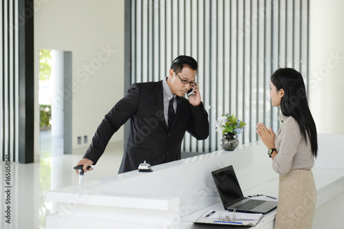 The receptionist greets the young businessman who is about to book the hotel room.