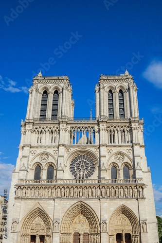 Notre Dame de Paris central main facade, national monument cathedral of France. French Gothic architecture. Sunny blue cloudy sky.