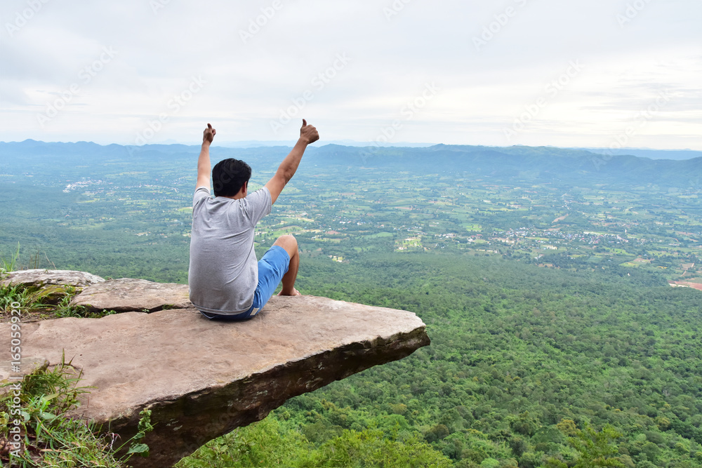 a man sitting on cliff at Pha Hum Hod, Sai Thong National Park, Chaiyaphum Province, Thailand.