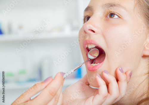 Close-up of little girl opening his mouth wide during treating her teeth by the dentist