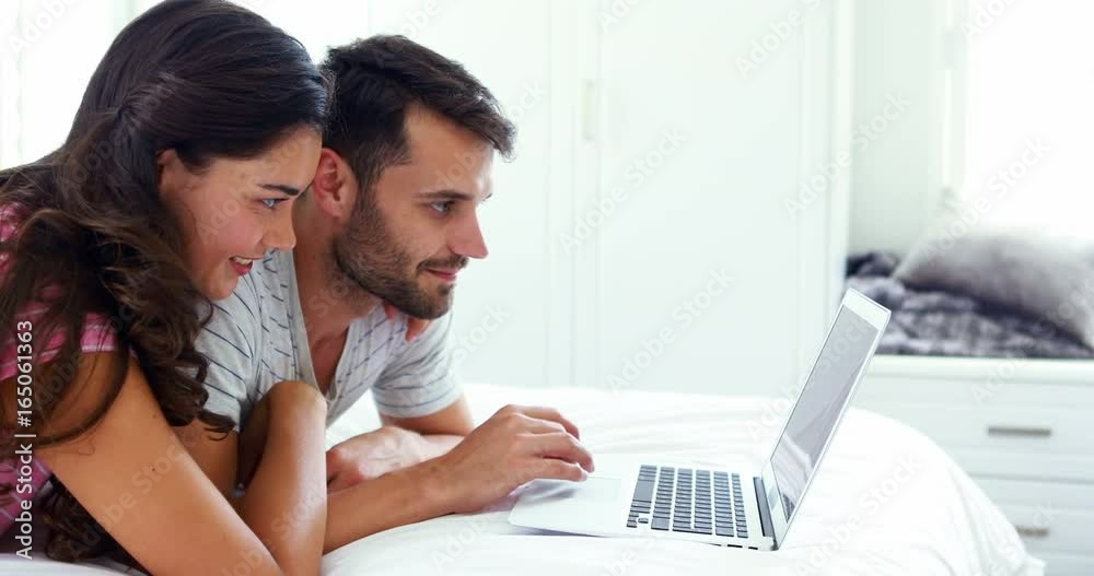 Couple interacting with each other while using laptop on bed Couple interacting with each other while using laptop on bed